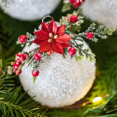 a white ornament with red flowers and greenery on it's side