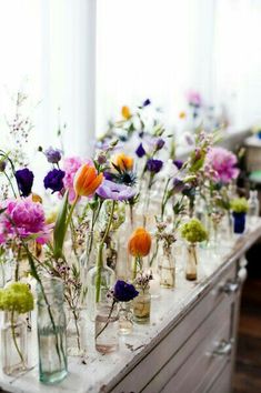 there are many vases with flowers in them