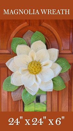 a wreath with a large white flower hanging on the front door to decorate it's entrance