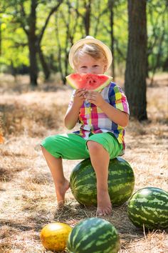 a young boy sitting on top of watermelon slices