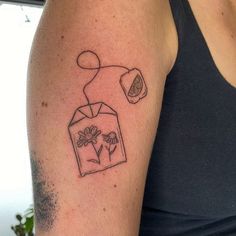 a woman's arm with a tattoo on it that has an image of a flower and a box