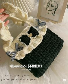 a hand holding a black and white crochet purse with bowknots