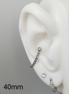 a pair of ear piercings sitting on top of a white plastic headpiece with crystal stones