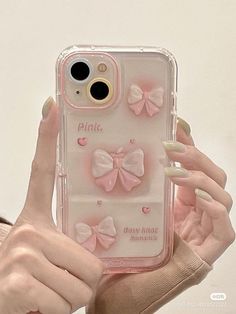 a woman holding up her phone case with pink bows on the front and back cover