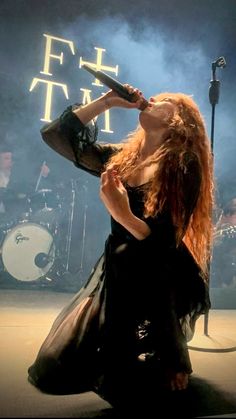 a woman with long red hair singing into a microphone