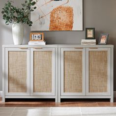 a white sideboard with wicker doors and drawers in a room next to a painting on the wall