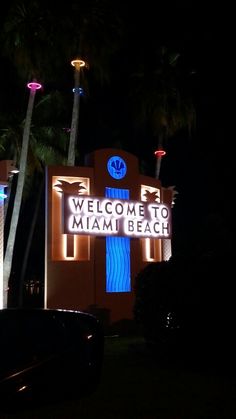 the welcome sign to miami beach lit up at night