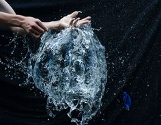 a person is holding their hand out to the water splashing from it's mouth