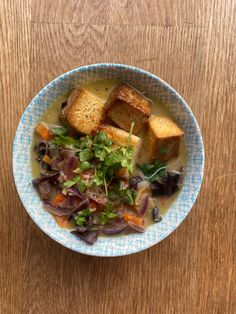 a blue and white bowl filled with food on top of a wooden table