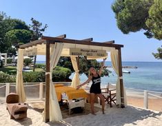 a woman sitting on top of a sandy beach under a gazebo