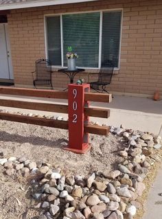 a red mailbox sitting in front of a house next to a gravel covered yard