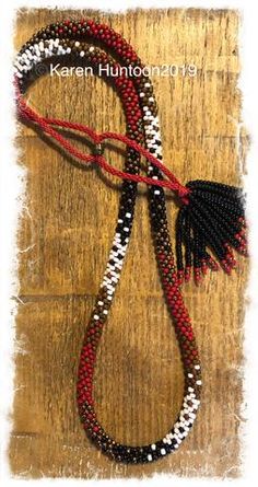 a red, white and black beaded necklace with tassels on wooden background