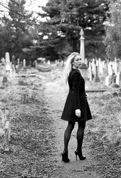 a woman standing in the middle of a cemetery