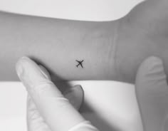 a person's arm with a small airplane tattoo on the left side of their arm