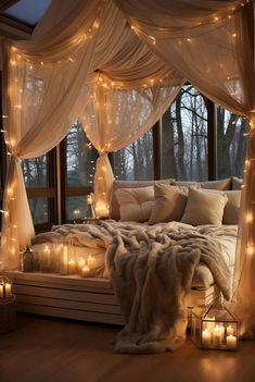 a canopy bed with lights hanging from it's sides and pillows on the floor