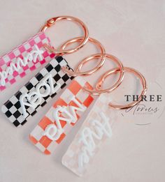 four key chains with different designs on them, one is pink and the other is white