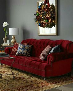 a living room with a red couch and christmas decorations on the wall above it,