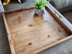 a wooden tray sitting on top of a gray couch next to a potted plant