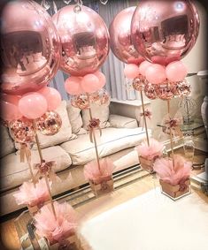 some pink balloons are on sticks in front of a couch