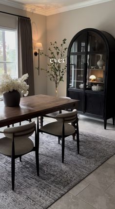 a dining room table with chairs and a vase filled with flowers on top of it