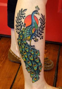 a person with a tattoo on their leg and a colorful peacock in the middle of it