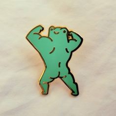 a green brooch with a bear on it's back and arms in the air