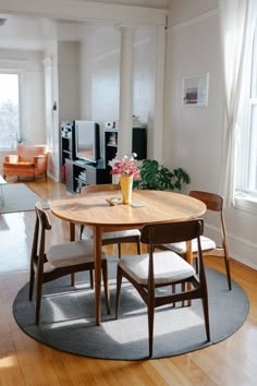 a wooden table with two chairs and a vase on it in the middle of a living room