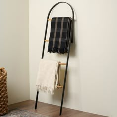 a towel rack with two towels hanging on it and a basket in the corner next to it