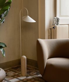 a living room with a chair, lamp and potted plant on the floor next to it