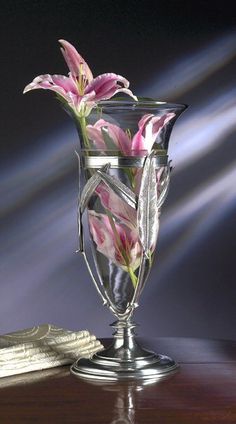 a glass vase with flowers in it sitting on a table next to some napkins