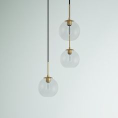 three glass globes hanging from the ceiling in an empty room with white walls and flooring