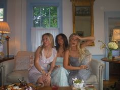 three women sitting on a couch in front of a table full of food and drinks