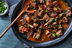 a pan filled with meat covered in sauce and garnished with parsley on the side