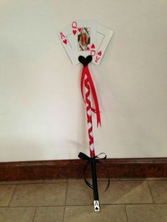 a pair of playing cards tied up to a wall with a red and white ribbon