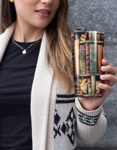 a woman holding up a cup with books on it