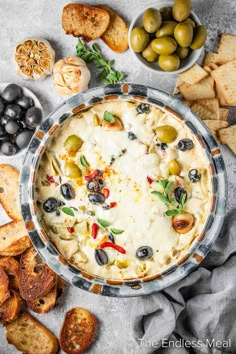 an overhead view of olives, cheese and crackers on a table with bread