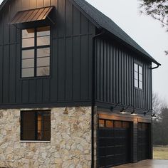 a black house with two garage doors and windows