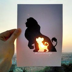 a person holding up a card with the silhouette of a lion on it in front of a cityscape