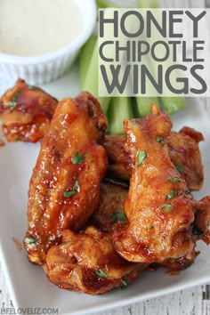 chicken wings and celery on a white plate with dipping sauce in the background