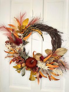 a wreath is hanging on the front door with autumn leaves and other things around it