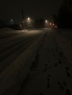 the road is covered in snow and there are footprints left on it at night time