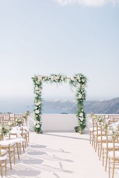 an outdoor ceremony setup with white flowers and greenery on the aisle, overlooking the ocean