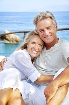 a man and woman sitting next to each other near the ocean