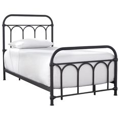 an iron bed frame with white sheets and pillows