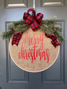 a christmas wreath hanging on the front door with red and black plaid ribbon around it