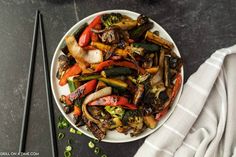 a white plate topped with vegetables next to chopsticks