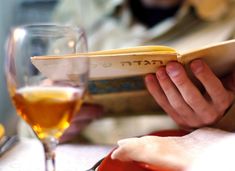 a person is reading a book at a table with wine glasses and bread in front of them