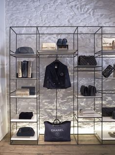 a clothing store display with clothes and bags on shelves in front of the glass wall