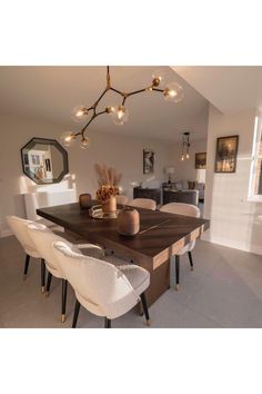 a dining room table and chairs with lights hanging from the ceiling