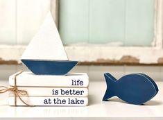 a wooden boat sitting on top of a stack of books next to a bookend